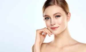 A woman touching her cheek after Radiesse® injections